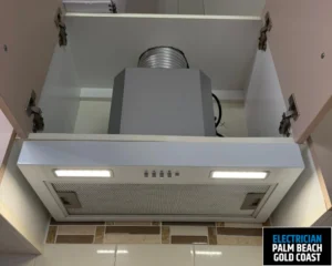 A modern kitchen rangehood installed under a cabinet with integrated lighting.